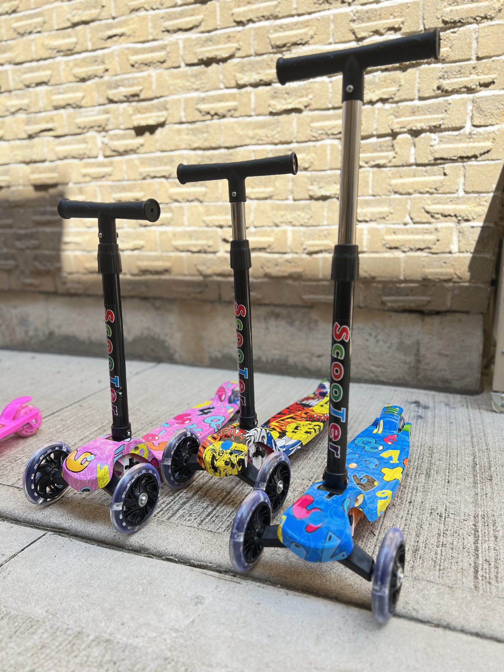 Kids graffiti-style blue three-wheel scooter with adjustable T-bar handle.